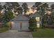 Two-story house with a two-car garage, lit windows, and a landscaped lawn at dusk at 1331 Pine Acre Dr, Sugar Hill, GA 30518