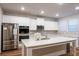 Bright kitchen features white cabinets, stainless steel appliances, and a large quartz island at 3004 Amabile Rd, Dacula, GA 30019