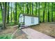 White storage shed nestled in a wooded backyard setting at 3054 Chelsea Ln, Acworth, GA 30102