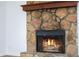 Close-up view of a stone fireplace with a wood mantel and a fire burning at 2729 Oxford Dr, Decatur, GA 30034