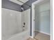 Bright bathroom featuring a white tiled shower-tub combo and a closet with white shelving for organization at 4127 Conley Pond Ct, Decatur, GA 30034