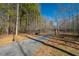 Paved driveway with black metal gate, surrounded by a beautiful natural landscape with lush trees at 4286 Pool Rd, Winston, GA 30187