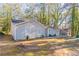 Gray sided single-story home with a spacious yard and mature trees surrounding the property at 1832 Vauxhall Dr, Lithonia, GA 30058