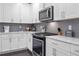 Modern kitchen with white cabinets, stainless steel appliances, and gray backsplash at 1968 Perry Nw Blvd, Atlanta, GA 30318