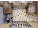Close up of the stainless steel stove top with granite countertops and tile backsplash at 3950 Stanford Dr, Cumming, GA 30041