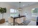 Bright dining area with large windows, a modern chandelier, and white upholstered chairs around a dark wood table at 405 Carrera Ln, Acworth, GA 30102