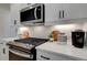 Close-up of a modern kitchen featuring stainless steel appliances, white cabinets, and quartz countertops at 405 Carrera Ln, Acworth, GA 30102