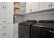 Neat laundry room featuring modern black appliances, white cabinets, and convenient shelving for organized storage at 290 Walker Ave, Alpharetta, GA 30076
