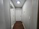 Neutral hallway featuring wood-look floors, multiple doors, and a ceiling light, providing access to rooms at 4908 Topsfield Ln, Lithonia, GA 30038