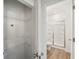 Open linen closet next to a modern bathroom with a glass-enclosed shower and plank flooring at 7268 Eton Ln, Locust Grove, GA 30248