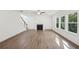Spacious living room with wood-look floors, fireplace, bright windows, and staircase at 7268 Eton Ln, Locust Grove, GA 30248