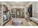 Large walk-in closet with custom shelving, hanging racks, a central ottoman, and stylish decor at 3612 Castlegate Nw Dr, Atlanta, GA 30327