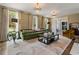 Bright living room featuring a tufted green sofa, elegant lighting, and large windows at 3612 Castlegate Nw Dr, Atlanta, GA 30327