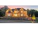 Elegant brick home with manicured lawn and stone retaining wall is well lit at dusk at 4927 Slaton Drive, Acworth, GA 30101