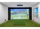 A golf simulator room with screen, projector, putting green and natural light from black-framed windows at 4927 Slaton Drive, Acworth, GA 30101