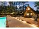 Exterior view of an A-frame home with a pool, outdoor seating, and string lights at dusk at 9650 Coleman Rd, Roswell, GA 30075