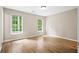 An empty room with wood-style floors, beige walls, and two double hung windows allowing natural light at 2382 Old Rex Morrow Rd, Ellenwood, GA 30294