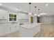 Open concept kitchen with an island, pendant lights, white cabinets, and hardwood floors at 1320 Melbenan Dr, Atlanta, GA 30311