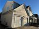 Side view of a two-story house with gray siding and a two-car garage at 681 Courageous Ct, Lawrenceville, GA 30043