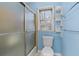 Blue bathroom with tiled shower and small window with shelving to the right of the toilet at 4116 River Cliff Chase Se, Marietta, GA 30067