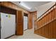 Hallway with two refrigerators and wood-paneled walls, adjacent to a wooden staircase at 4116 River Cliff Chase Se, Marietta, GA 30067