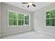 Cozy bedroom with white walls, light carpet, a ceiling fan, and large windows with wooded views at 101 Forsyth Park Ln, Woodstock, GA 30188