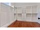 Well-organized walk-in closet with built-in shelving, drawers, and hanging rods on hardwood floors at 101 Forsyth Park Ln, Woodstock, GA 30188