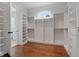 Spacious walk-in closet with custom shelving, drawers, and hanging rods on hardwood floors at 101 Forsyth Park Ln, Woodstock, GA 30188