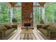 Relaxing covered porch features a stone fireplace, wood flooring, comfortable seating, and scenic wooded views at 101 Forsyth Park Ln, Woodstock, GA 30188