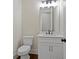 Modern half bathroom with a white vanity, a mirror, and a toilet; features a clean and simple design at 101 Forsyth Park Ln, Woodstock, GA 30188