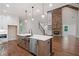 Open kitchen view showcasing a stone fireplace, stainless steel appliances, and hardwood floors at 101 Forsyth Park Ln, Woodstock, GA 30188