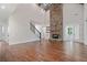 Open living room with a soaring stone fireplace, hardwood floors, staircase, and view of an additional room at 101 Forsyth Park Ln, Woodstock, GA 30188