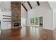 Bright open living room featuring soaring stone fireplace, wood beams, hardwood floors, and access to the outdoors at 101 Forsyth Park Ln, Woodstock, GA 30188