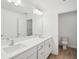 Bright bathroom featuring a double sink vanity with a framed mirror and white cabinets at 7256 Eton Ln, Locust Grove, GA 30248