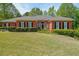 Traditional home with a well-manicured lawn, brick exterior, black shutters and mature landscaping at 1420 Arblay Pl, Loganville, GA 30052