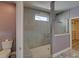 Modern bathroom featuring tile shower, bench, small window and walk-in closet at 5860 Collier Bridge Ln, Hoschton, GA 30548