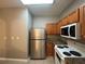 Kitchen area with stainless steel refrigerator, white appliances, and wood cabinets at 4461 Ravenwood Dr, Union City, GA 30291