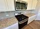 Close-up view of stainless steel stove and microwave with granite counters and light tile backsplash at 2422 Brown Dove Way Lot 70, Grayson, GA 30017