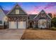 Sunset view of a beautiful stone-accented home featuring a two-car garage and landscaped front yard at 173 Mill Creek Dr, Canton, GA 30115