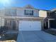 Two-story brick home with a white double garage door and landscaping at 10954 Wheeler Trce, Hampton, GA 30228