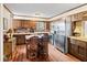 Warm kitchen with stainless steel appliances, wood cabinets and flooring, with an island and two chairs at 837 Pine Ridge Dr, Lawrenceville, GA 30043