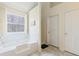 Bright bathroom with a soaking tub set under a large window and marble floors at 6834 Fireside Ln, South Fulton, GA 30349