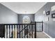Upstairs hallway featuring black wood bannister and gray walls with large window at the far end of the hall at 6834 Fireside Ln, South Fulton, GA 30349