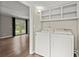 Well-lit laundry room with washer, dryer, and storage shelves at 855 Riverbend Sw Dr, Lilburn, GA 30047