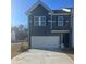 Two-story townhome with gray siding, white garage door, and landscaping at 1200 Westhampton Way # 141, Villa Rica, GA 30180