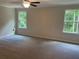 Spacious bedroom with neutral walls, carpet, and two windows overlooking a green, wooded area at 1356 Lucan Ln # Wc226, Lawrenceville, GA 30043