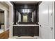 Dark wood vanity with granite countertop and patterned wallpaper at 4844 Elkhorn Hill Dr, Suwanee, GA 30024