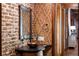 Elegant powder room features brick wall, patterned wallpaper, and a copper sink at 4844 Elkhorn Hill Dr, Suwanee, GA 30024