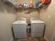 A functional laundry room with a washer, a dryer, and shelving for storage at 3280 Hallmark Ln, Buford, GA 30519