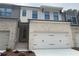 New construction townhome features a two-car garage, light brick, black gutters, and a yellow front door at 1366 Lucan Ln # Wc225, Lawrenceville, GA 30043